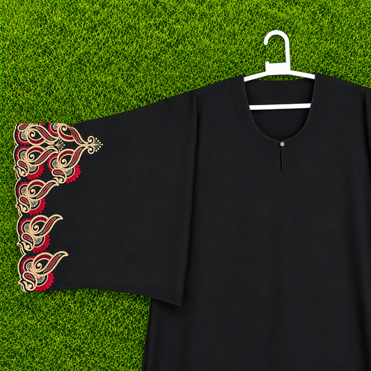 A black long-sleeve tunic or abaya with ornate red and gold embroidered cuffs, displayed on a white hanger against a green grass background.